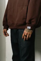 Canguro marrón con capucha, corte oversize y logo bordado en el pecho.