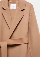 Abrigo largo color camel de lana reciclada con diseño oversize, cuello con solapa, manga larga, dos bolsillos delanteros, cinturón desmontable y abertura posterior en el bajo.