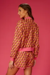 Short de playa con estampado geométrico en tonos naranja, amarillo y rosa. Cintura elástica y ribete rosa.