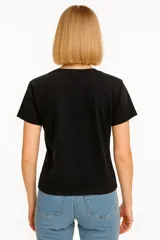 Remera celeste de manga corta y cuello redondo, con estampado de sardinas sobre fondo a cuadros rojos y blancos. Incluye texto con los nombres de las ciudades de Cagliari y Sardina.