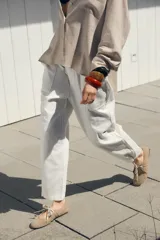 Pantalón color beige de tiro medio con cintura elástica ajustable con cordones, bolsillos delanteros y falsos bolsillos de vivo en la espalda. El bajo es ajustable con botón a presión.