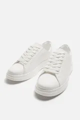 Zapatillas deportivas blancas, de estilo minimalista, con cordones y suela gruesa.