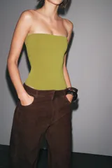 Body bandeau color verde oliva confeccionado en tejido elástico, con escote recto y hombros descubiertos. Cierre inferior con botones a presión.