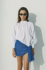 Blusa blanca de lino con cuello fruncido y botones frontales.