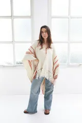 Ruana artesanal color crudo con rayas horizontales color ladrillo y flecos.