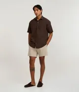 Bermuda de microfibra color beige, con cintura elástica y cordón ajustable. Presenta textura en el tejido y un bolsillo lateral.