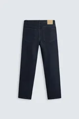 Jeans de corte slim fit confeccionados en denim de algodón sin lavados, color azul oscuro. Cierre frontal con botones y cinco bolsillos.