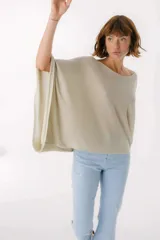 Blusa beige de tejido brillante, con cuello bote y mangas murciélago.