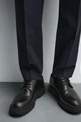 Zapato de vestir estilo derby, color negro, con capellada de cuero, horma redonda y suela de goma con volumen.