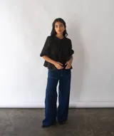 Blusa negra de popelina de algodón con corte peplum, mangas abullonadas y lazo en el cuello.