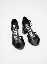 Sandalias de charol negro con tiras finas cruzadas en el empeine, pulsera al tobillo con hebilla y tacón cuadrado.