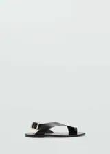Sandalias negras de cuero con tira cruzada y hebilla dorada.