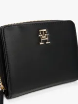 Billetera Tommy Hilfiger negra con cierre de cremallera y logo TH dorado en el frente. Cuenta con múltiples ranuras interiores para tarjetas y compartimento para billetes.