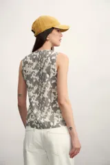 Chaleco sin mangas con escote en V y cierre frontal de botones dorados. Presenta un estampado tipo ikat o batik en blanco y negro.