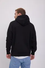 Canguro negro de manga larga con capucha, corte relajado y bolsillo tipo canguro. Estampado frontal con la inscripción "Originals Studio Brought to you by Jack&Jones Designed in Copenhagen".