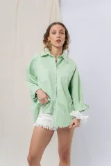 Camisa color crema de algodón liviano, calce oversize, con cuello camisero, cierre abotonado, mangas largas con opción de arremangado y dos bolsillos frontales con solapa.