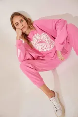 Buzo rosa con cuello redondo y estampado de flores blancas formando un corazón en el frente.