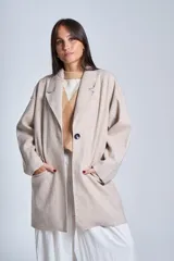 Tapado gris oscuro de corte oversize, con solapa clásica, hombros caídos, cierre con un botón central y bolsillos laterales funcionales.