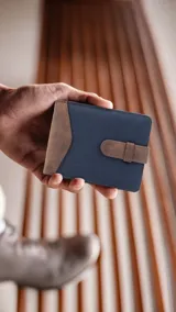 Billetera azul marino y marrón de símil cuero y tela canvas con presilla. Interior con visor, doble repartición para billetes, tarjeteros y bolsillo.
