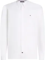 Camisa blanca de Tommy Hilfiger de corte slim fit, manga larga y cuello abotonado. Tiene el logo de la marca bordado en el pecho.