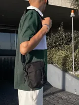 Bandolera negra con correa ajustable y cinco bolsillos.