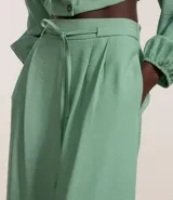 Pantalón wide leg color verde agua, de tiro alto y corte sastrero, con cintura elástica en la espalda, cinturón incorporado para lazo, pliegues delanteros y bolsillos laterales.