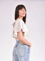 Blusa corta a rayas horizontales color beige y blanco, con mangas cortas con volados y elástico en la cintura.