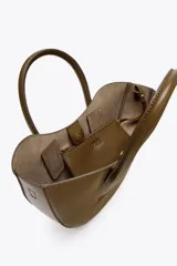 Bolso shopper de mano color marrón, con asa doble y correa bandolera extraíble. Tiene cierre imantado y un bolsillo interior con cremallera.