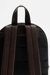 Mochila marrón oscuro de cuero, con compartimento principal con cierre de cremallera, bolsillo interno plano y bolsillo interno con cremallera. Bolsillo frontal con cremallera, parte posterior acolchada con banda de sujeción para equipaje, asa de mano y dos asas de hombro ajustables.