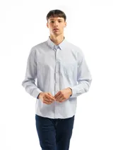 Camisa celeste y blanca a rayas verticales, de manga larga y corte clásico. Tiene cuello abotonado y bolsillo en el pecho.