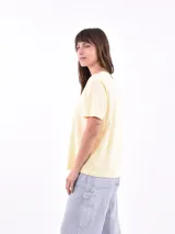 Remera color amarillo claro con estampado de limones, hojas y flores en tonos verdes y grises.