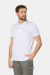 Remera polo blanca de jersey de algodón, con cuello y mangas con ribete azul. Logo bordado en el pecho y botones color madera.