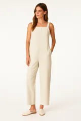 Mono de viscosa color crema con rayas verticales finas, breteles anchos, corte holgado, cierre trasero y cuello recto.