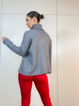 Sweater gris con cuello alto y corte asimétrico.