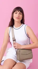 Bandolera color beige de cuero sintético con dos compartimentos principales con cierre, bolsillo interno y correa de tela regulable. Incluye un bolsillo trasero con cierre y un bolsillo frontal con botón.