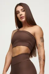 Top deportivo negro de un solo hombro, con textura acanalada y calce ajustado.