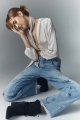 Pantalón de jean de tiro alto, denim azul rígido con lavado localizado y apliques de brillos. Pierna recta y ruedo desflecado.