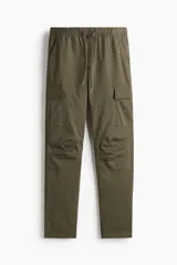 Pantalón cargo color verde oliva, de corte slim fit, con cintura elástica ajustable con cordón, bolsillos laterales al bies y bolsillos cargo con solapa y botón a presión en los muslos.