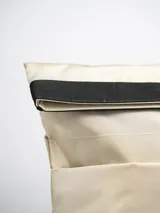 Mochila color beige con cierre superior enrollable y hebilla de ajuste.