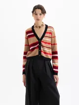 Cardigan corto de punto con estampado de rayas onduladas en tonos beige, rojo, rosa y blanco. Tiene cuello en V, botones frontales y ribetes negros en el escote y puños.