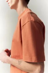 Remera color salmón de corte holgado, cuello redondo y mangas cortas.