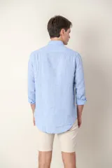 Camisa celeste de lino con cuello clásico y manga larga. Presenta un pequeño logo bordado en el pecho.