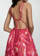 Vestido largo con estampado floral en tonos rosados y anaranjados, con escote en V, tirantes finos y espalda descubierta con cierre de lazo.