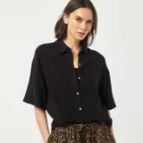 Camisa negra de lino con corte holgado, cuello clásico, manga corta y cierre frontal con botones.