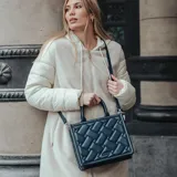 Bolso tote azul marino con diseño acolchado en símil cuero, doble asa corta y correa larga regulable.