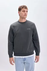 Sudadera gris oscuro de corte clásico con cuello redondo y puños y bajo acanalados. Presenta un pequeño bordado con letras en el pecho.