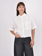 Camisa blanca de mangas cortas con cuello clásico y bolsillo en el pecho.