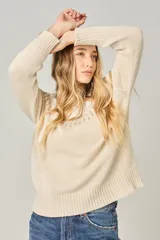 Sweater tejido color verde agua con cuello redondo y diseño de ochos con detalles rosados en la parte superior.