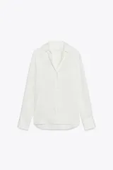 Camisa de mujer satinada color blanco, confeccionada en hilatura con viscosa. Tiene cuello solapa, manga larga con puños y cierre frontal con botones.