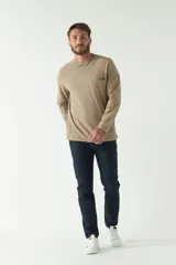 Remera color marrón de manga larga, con bolsillo en el pecho y logo de la marca en etiqueta sobre el bolsillo.